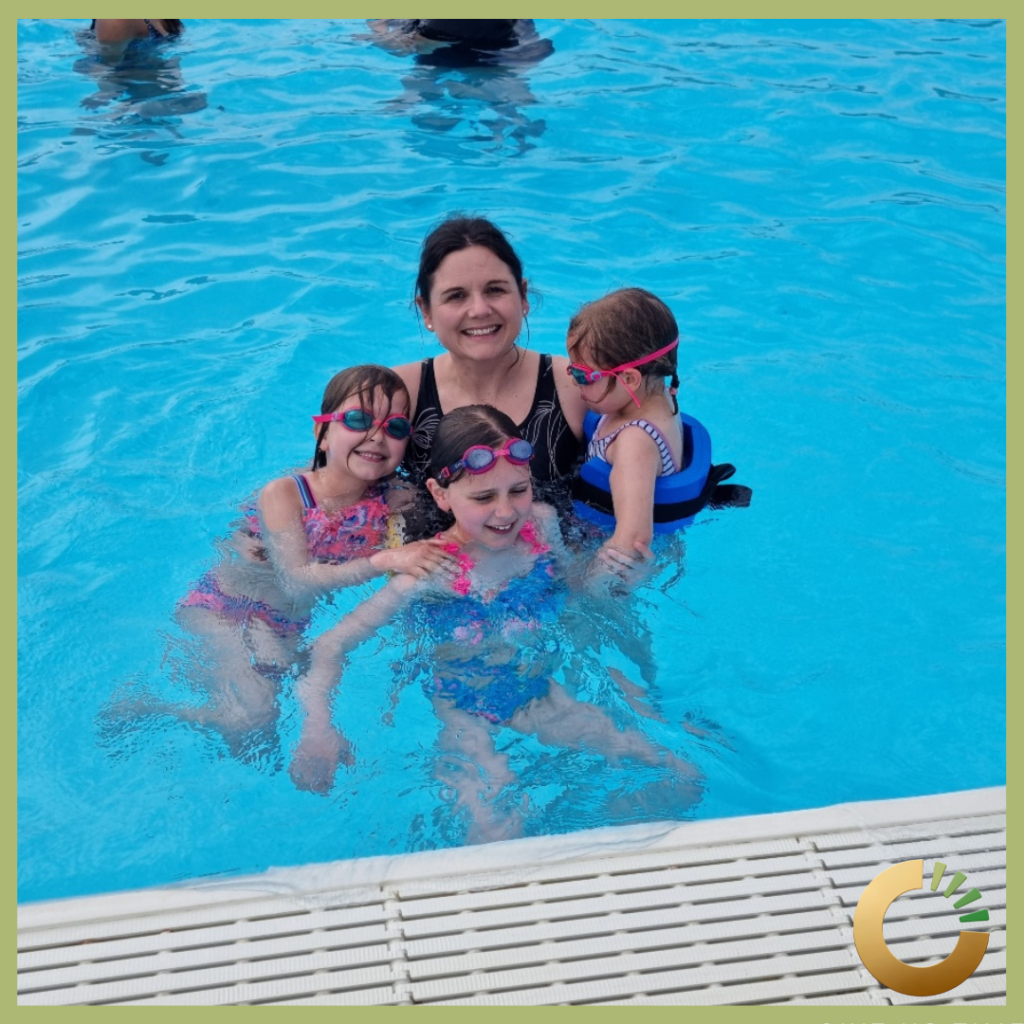 a woman and three children in a swimming pool. they are all smiling